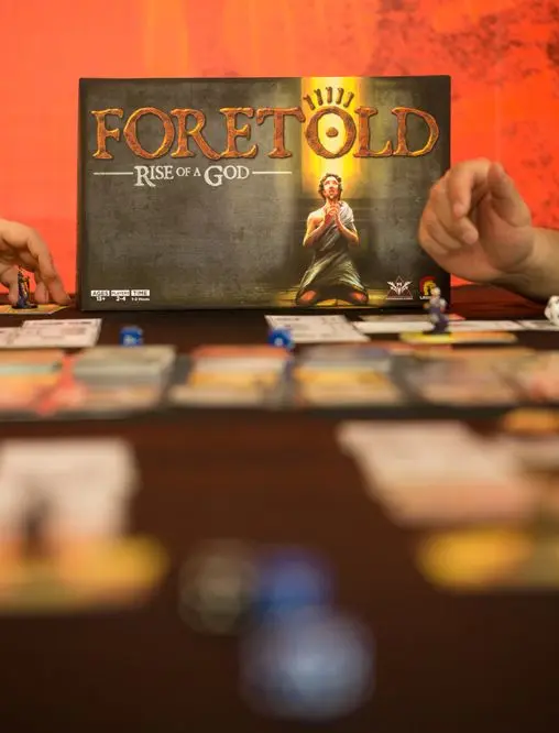 Players gathered around a table playing Foretold: Rise of a God